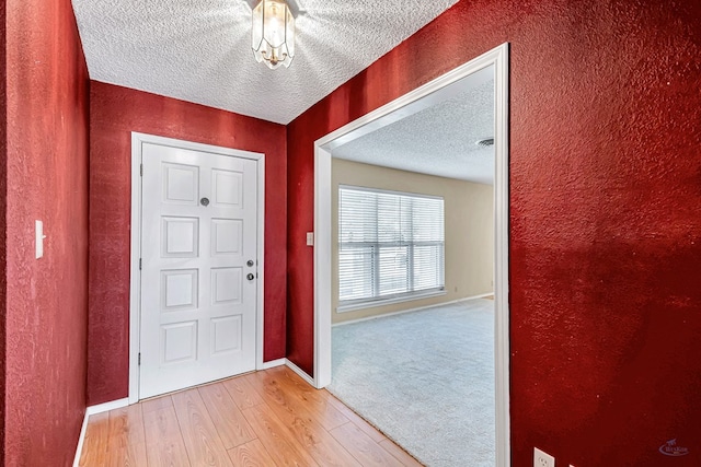 foyer entrance featuring a textured ceiling and light wood-type flooring