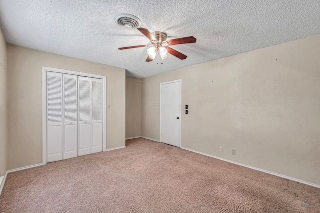 unfurnished bedroom with ceiling fan, carpet floors, a closet, and a textured ceiling