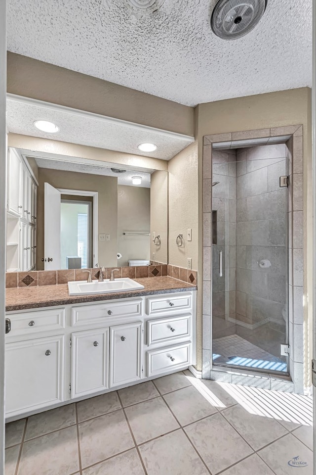 bathroom featuring vanity, a shower with door, tile patterned flooring, and a textured ceiling