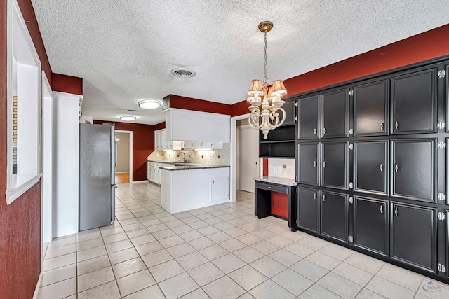 kitchen featuring light tile patterned flooring, stainless steel refrigerator, decorative light fixtures, decorative backsplash, and a notable chandelier