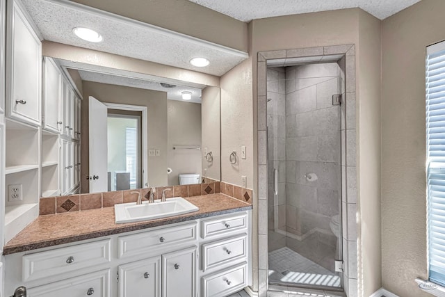 bathroom with vanity, walk in shower, a textured ceiling, and toilet