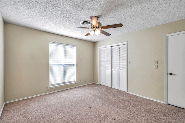 unfurnished bedroom with ceiling fan, carpet flooring, a textured ceiling, and a closet