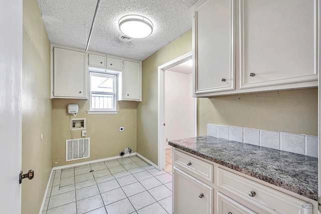 washroom with light tile patterned flooring, cabinets, a textured ceiling, washer hookup, and hookup for an electric dryer