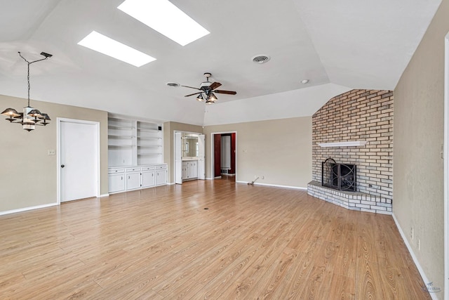 unfurnished living room featuring ceiling fan with notable chandelier, a fireplace, lofted ceiling, light hardwood / wood-style floors, and built in shelves