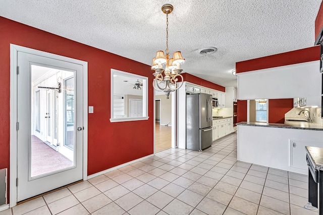 kitchen with pendant lighting, sink, white cabinetry, stainless steel appliances, and a notable chandelier