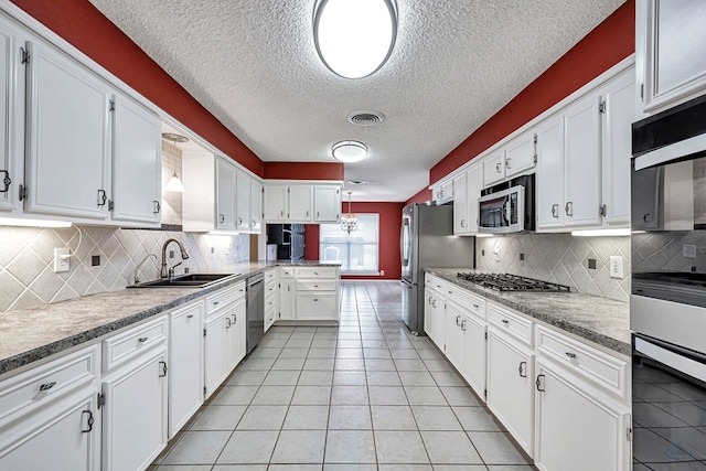 kitchen featuring white cabinetry, sink, light tile patterned floors, and appliances with stainless steel finishes