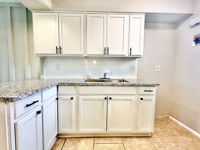 501 W Scharbauer Dr Unit 28, Midland, TX 79705 - kitchen featuring white cabinets, light stone counters, decorative backsplash, and a sink