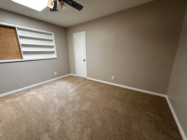 unfurnished room featuring carpet, built in features, a ceiling fan, and baseboards