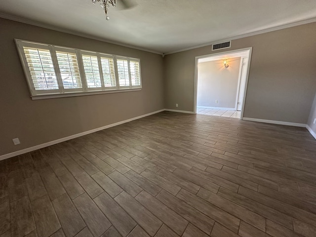 unfurnished room featuring baseboards, dark wood finished floors, visible vents, and crown molding