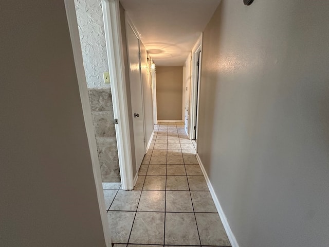 corridor with light tile patterned flooring and baseboards