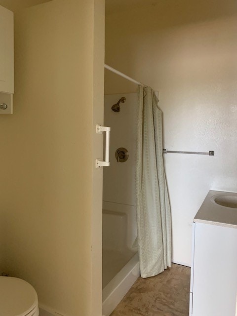 bathroom with toilet, vanity, and walk in shower