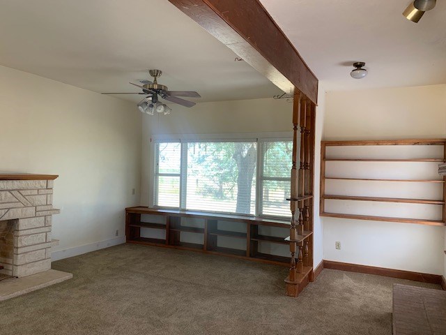 unfurnished living room featuring ceiling fan, carpet floors, and a fireplace