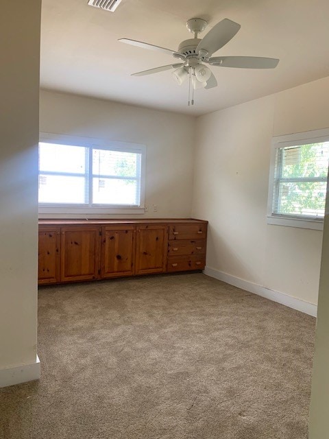 carpeted empty room with ceiling fan and a healthy amount of sunlight