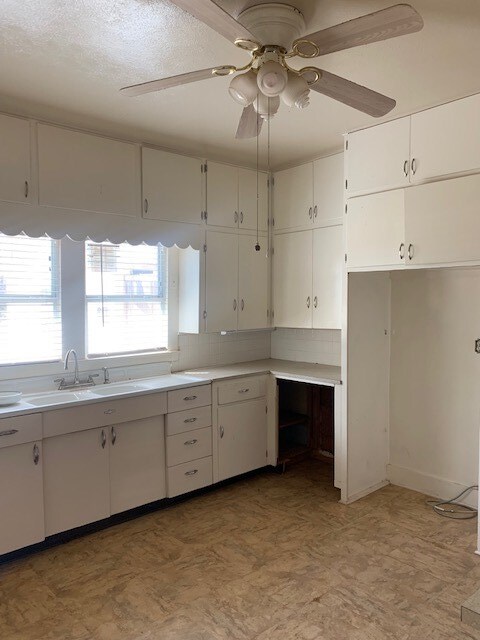 kitchen with backsplash, white cabinetry, ceiling fan, and sink