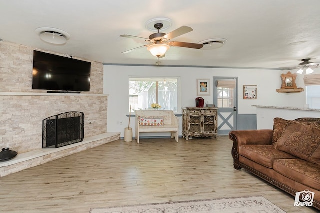 3228 W Dengar Ave, Midland, TX 79705 - living room with a ceiling fan, a fireplace, light wood-style floors, and plenty of natural light