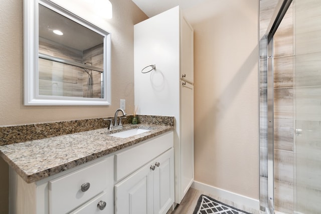 bathroom with a shower with door, vanity, and hardwood / wood-style flooring