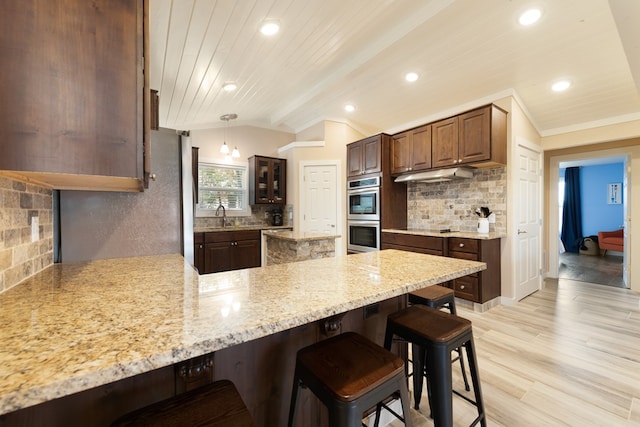 kitchen featuring backsplash, light hardwood / wood-style floors, hanging light fixtures, and lofted ceiling