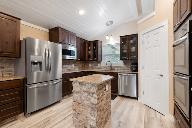 kitchen featuring hanging light fixtures, stainless steel appliances, tasteful backsplash, light stone counters, and vaulted ceiling