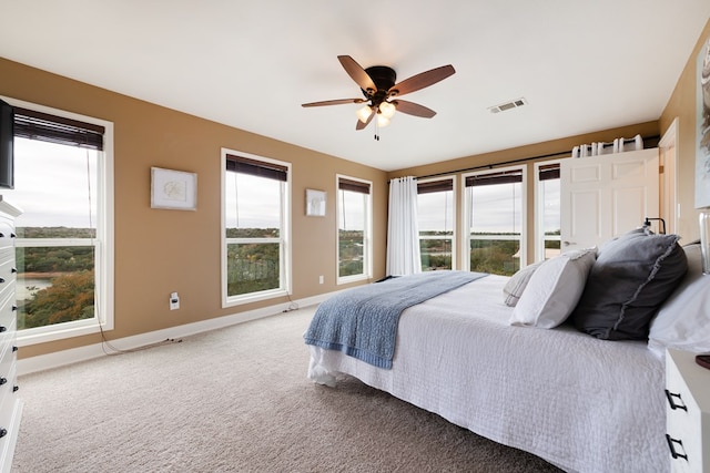 carpeted bedroom featuring ceiling fan and a fireplace