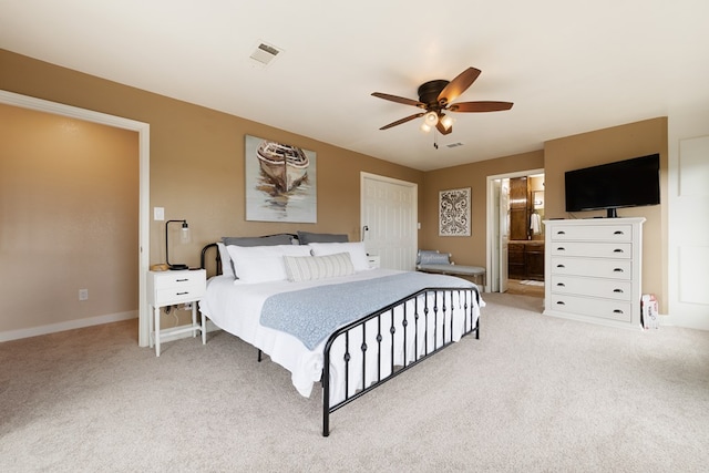 bedroom featuring light carpet, a closet, ensuite bath, and ceiling fan