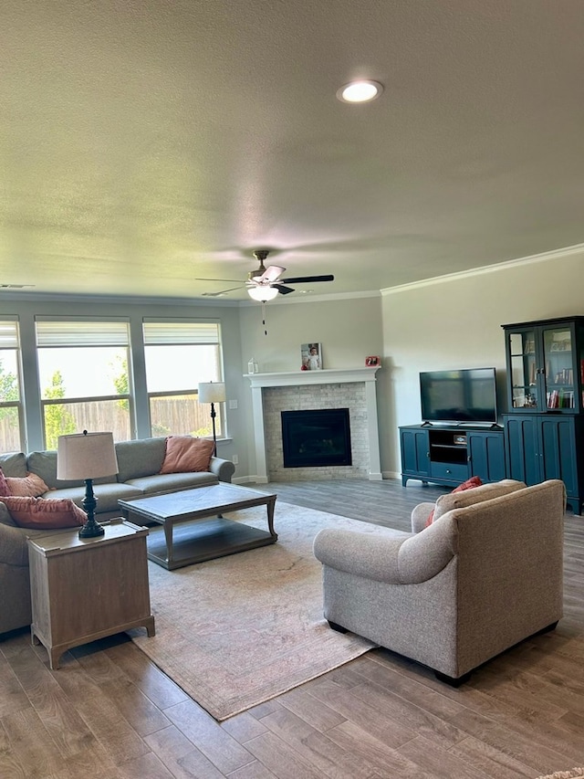 7103 Mcpherson Ln, Midland, TX 79706 - living area featuring a ceiling fan, wood finished floors, a fireplace, a textured ceiling, and ornamental molding