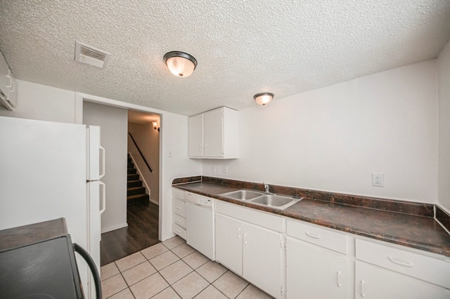 kitchen with a textured ceiling, white cabinetry, sink, and white appliances