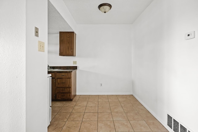 unfurnished dining area with sink, light tile patterned floors, and a textured ceiling