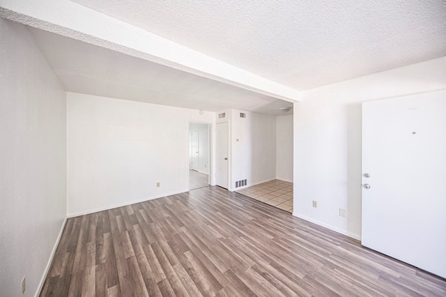 spare room featuring wood-type flooring and a textured ceiling