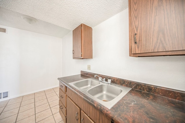 kitchen with a textured ceiling, light tile patterned floors, and sink