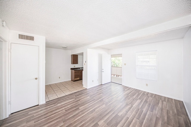 unfurnished living room with light hardwood / wood-style floors and a textured ceiling