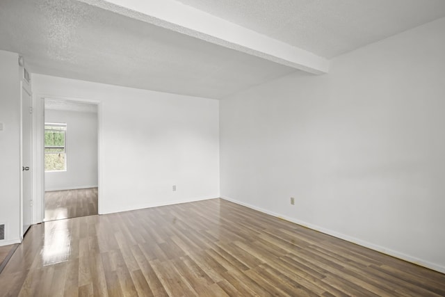 unfurnished room featuring beam ceiling, a textured ceiling, and hardwood / wood-style flooring