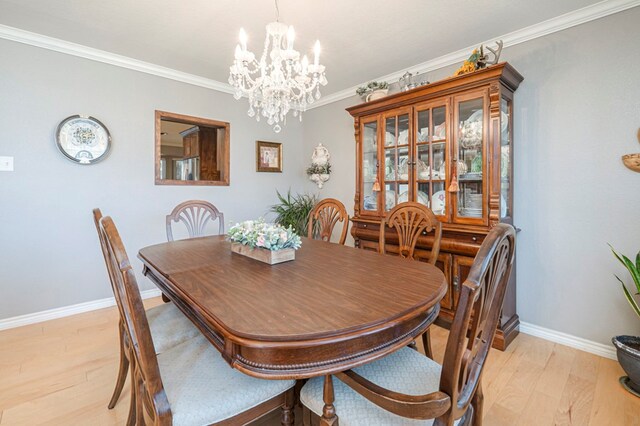 dining space featuring ornamental molding, a notable chandelier, and light wood-type flooring