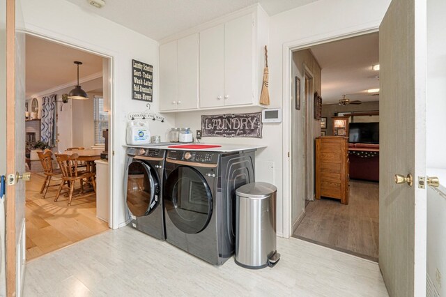 clothes washing area with ornamental molding, light hardwood / wood-style floors, cabinets, and washing machine and clothes dryer