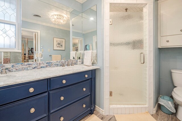 bathroom featuring vanity, hardwood / wood-style flooring, toilet, ornamental molding, and a shower with shower door