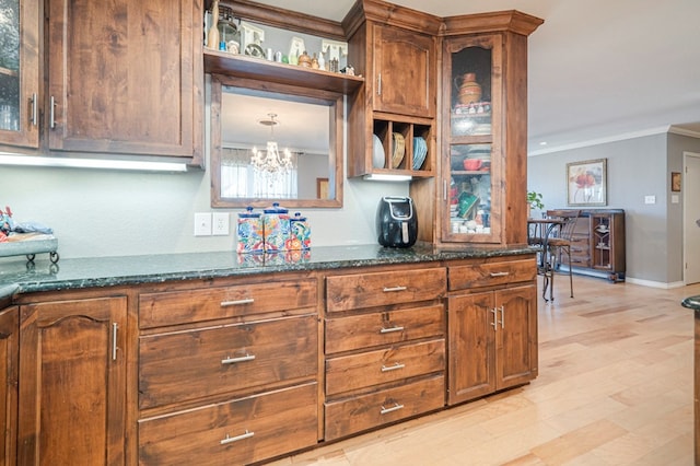 kitchen with light hardwood / wood-style floors, dark stone counters, and ornamental molding