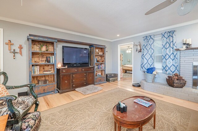 living room featuring ceiling fan, crown molding, a fireplace, and hardwood / wood-style floors