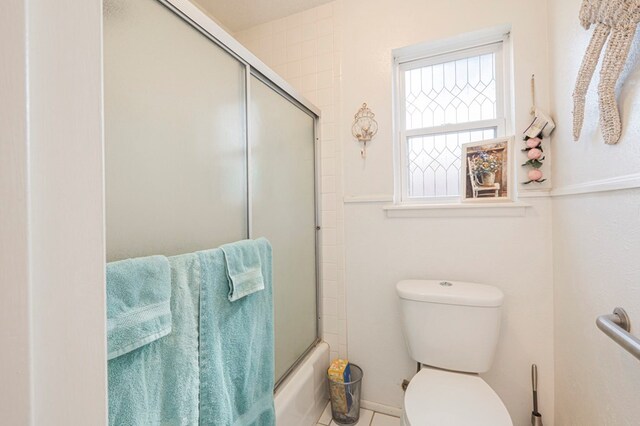 bathroom featuring bath / shower combo with glass door and toilet