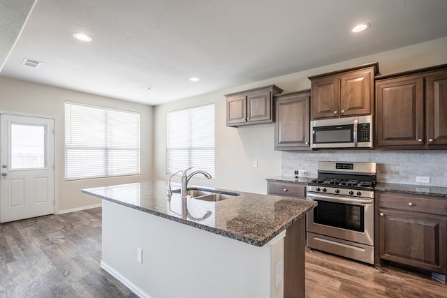 7318 Cross B Rd, Odessa, TX 79765 - kitchen with stainless steel appliances, dark stone counters, wood finished floors, backsplash, and recessed lighting