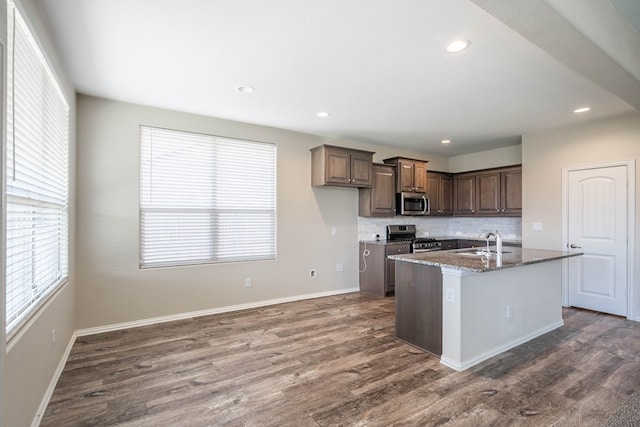 7318 Cross B Rd, Odessa, TX 79765 - kitchen featuring stainless steel appliances, backsplash, dark wood-style flooring, dark stone counters, and recessed lighting