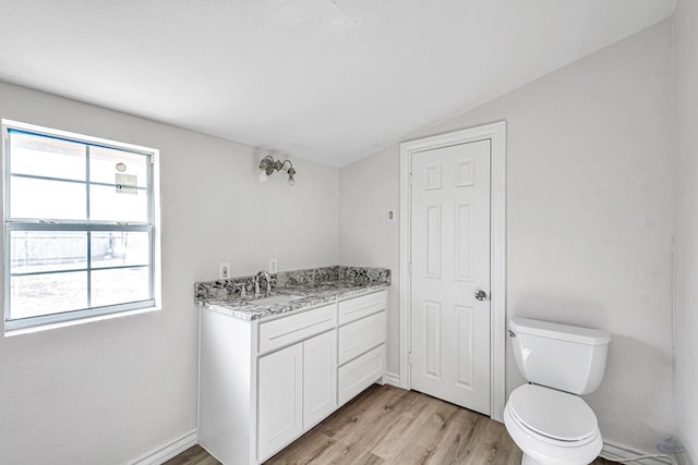 bathroom featuring hardwood / wood-style floors, vanity, lofted ceiling, and toilet