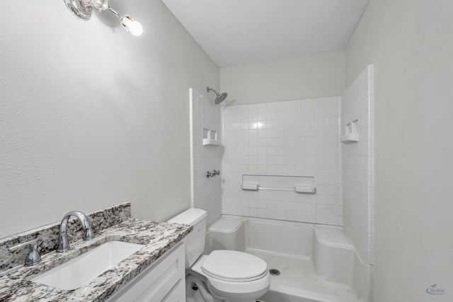 bathroom with a tile shower, vanity, and toilet