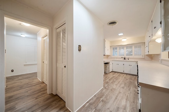 hall with light wood-style floors and visible vents