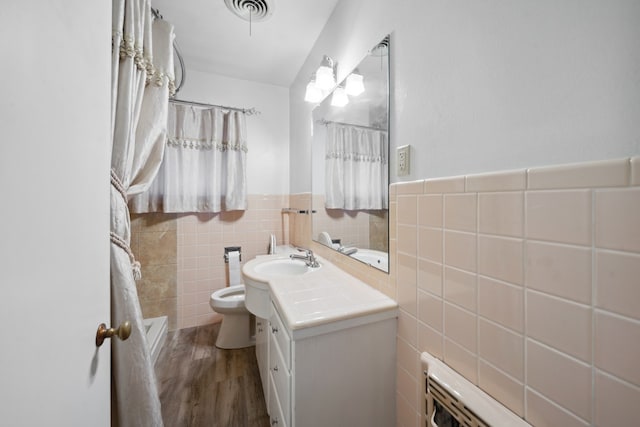 bathroom with tile walls, visible vents, toilet, wood finished floors, and vanity