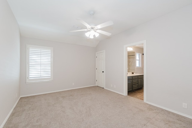 unfurnished bedroom with multiple windows, lofted ceiling, sink, and light colored carpet