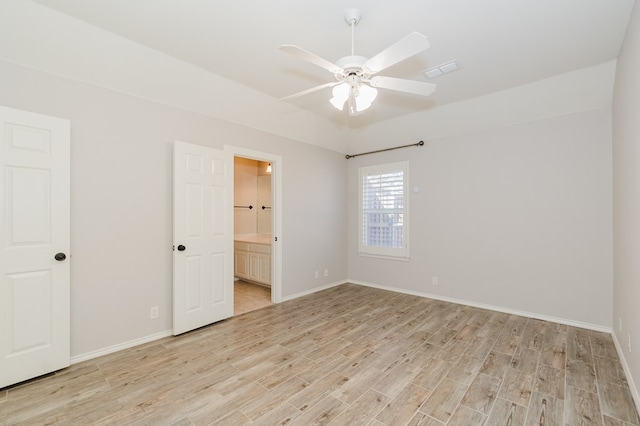 unfurnished bedroom featuring ensuite bathroom, vaulted ceiling, and light wood-type flooring