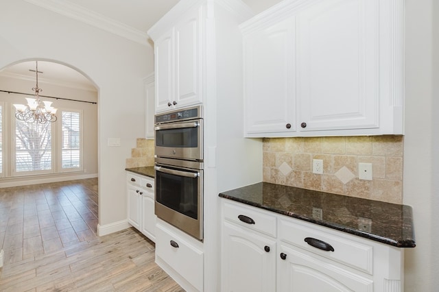 kitchen with dark stone countertops, stainless steel double oven, and white cabinets