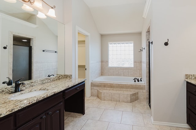 bathroom featuring lofted ceiling, tiled tub, tile patterned flooring, and vanity