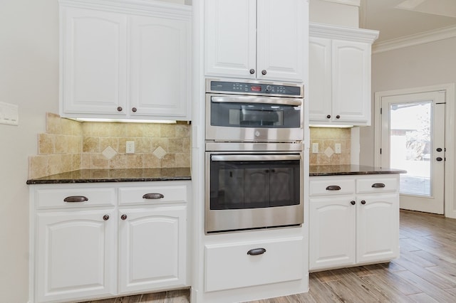 kitchen featuring white cabinetry, dark stone countertops, and double oven