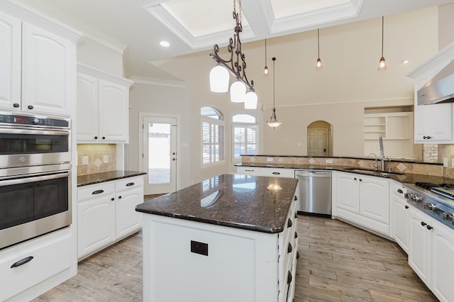 kitchen with sink, appliances with stainless steel finishes, white cabinetry, a kitchen island, and decorative light fixtures