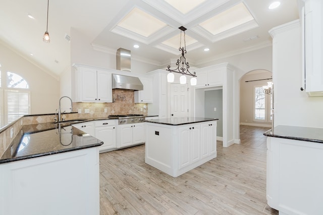 kitchen featuring white cabinetry, sink, hanging light fixtures, kitchen peninsula, and wall chimney exhaust hood